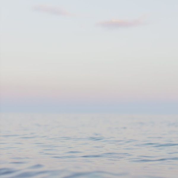 Man meditating peacefully outdoors with a serene landscape background.